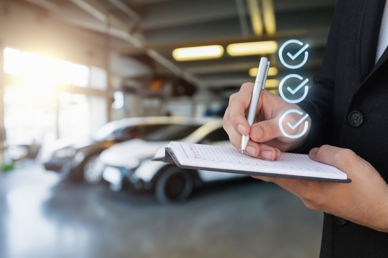 Person writing notes on a clipboard in front of a car